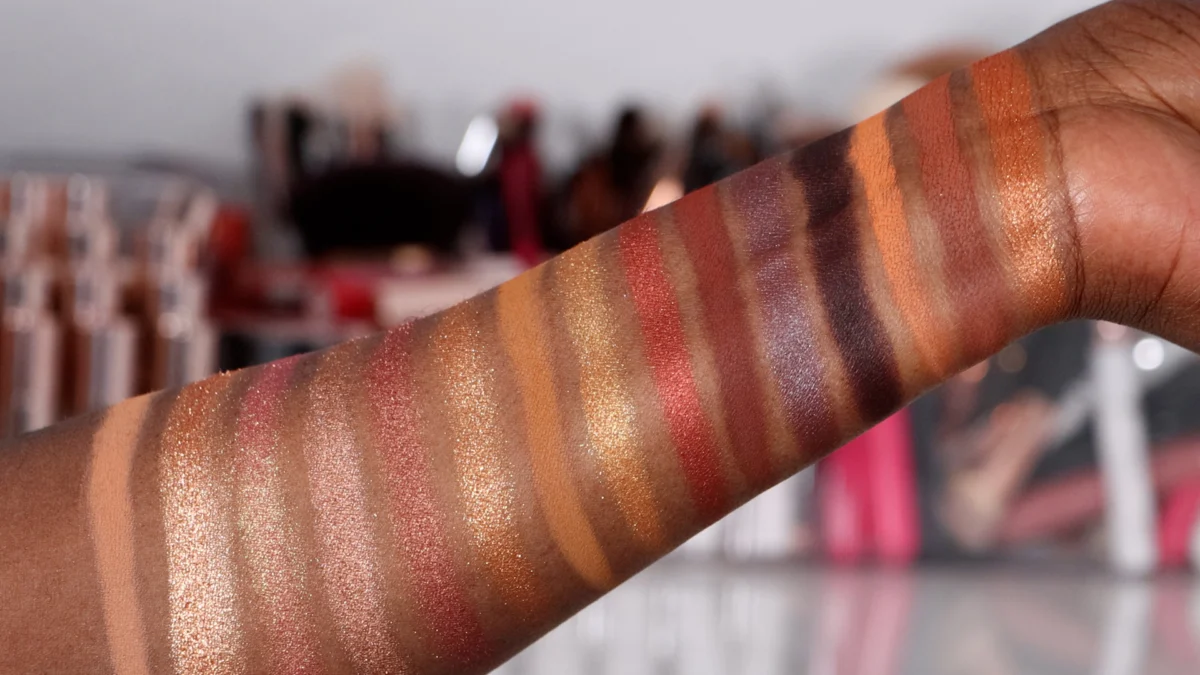 Hand showing multiple eyeshadow swatches in different shades.