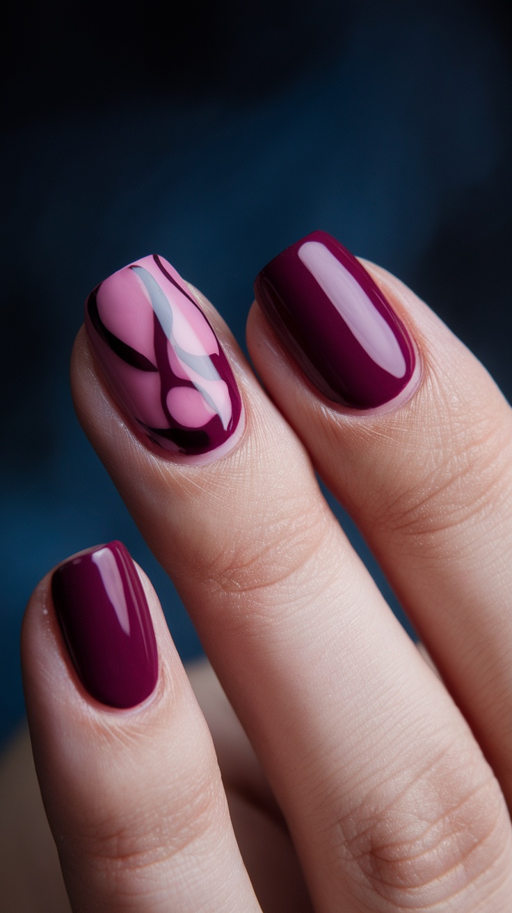  February Nail Ideas: Close-up of bold berry and plum nails with a pink accent design.