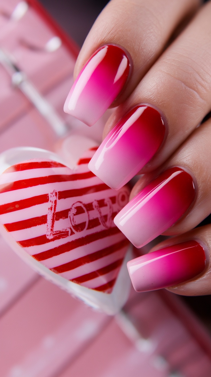 Close-up of red and pink ombre nails with heart decoration in the background