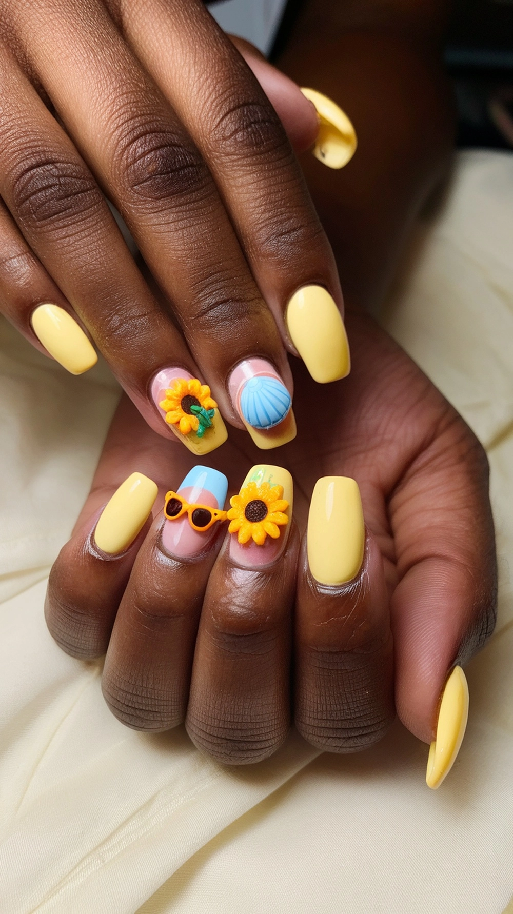 A close-up of butter yellow nails with decorative summer-themed designs.