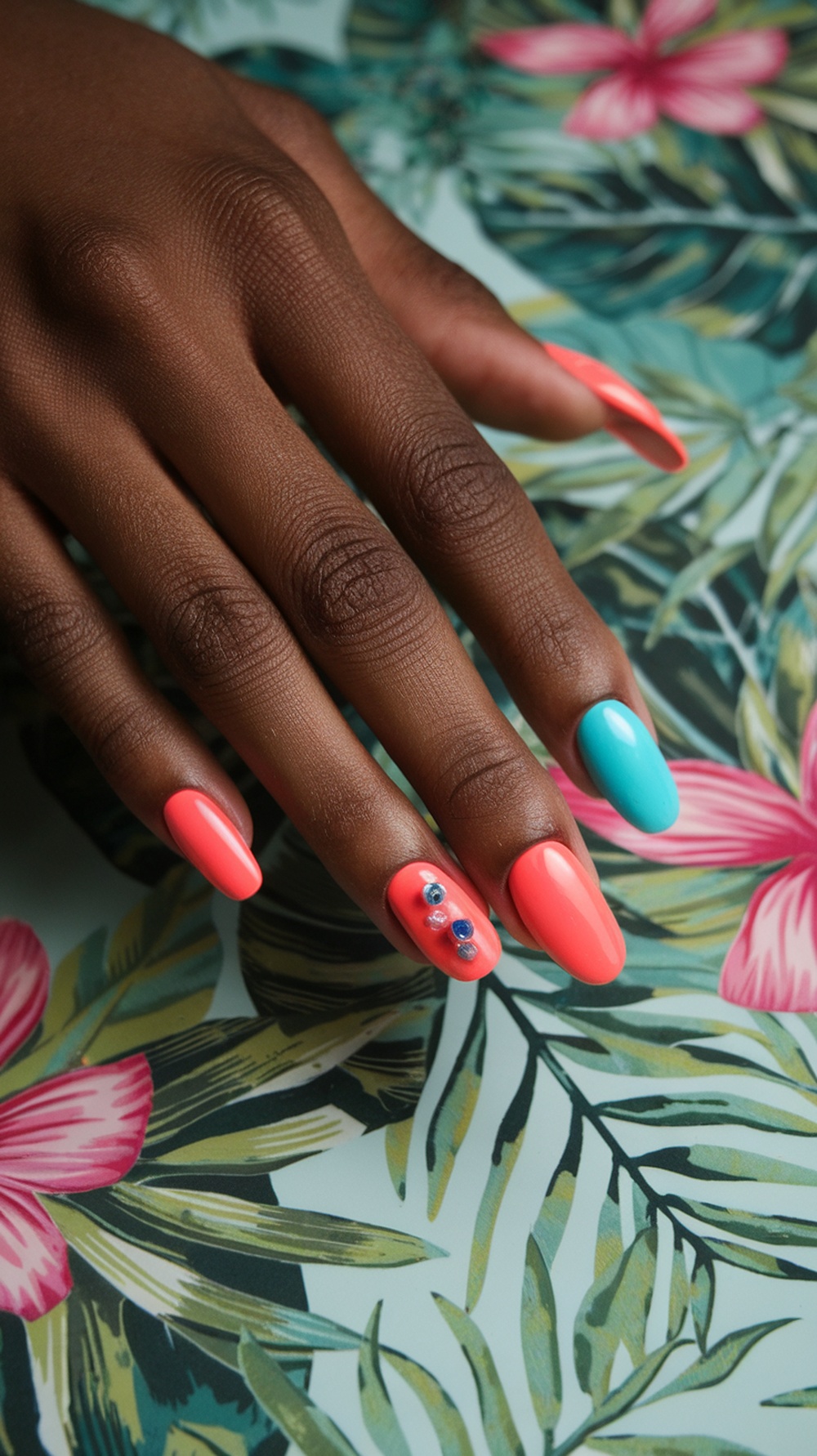 Bright coral and aqua nails with accents, set against a tropical floral background.