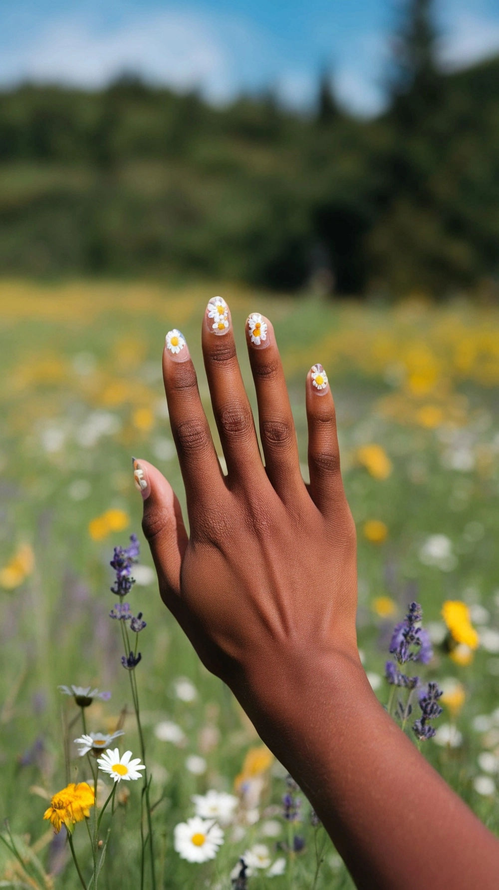 A hand with wildflower nail art in a field of flowers