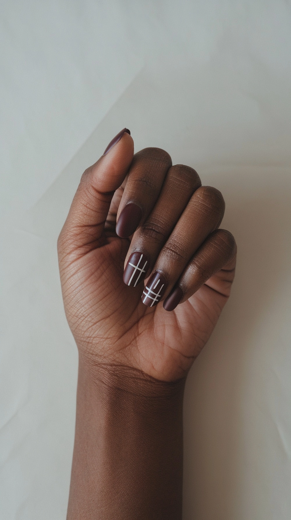 How to Style Burgundy Nail Designs for a Bold Stunning Look 22 A hand showing burgundy nails with minimalist white designs