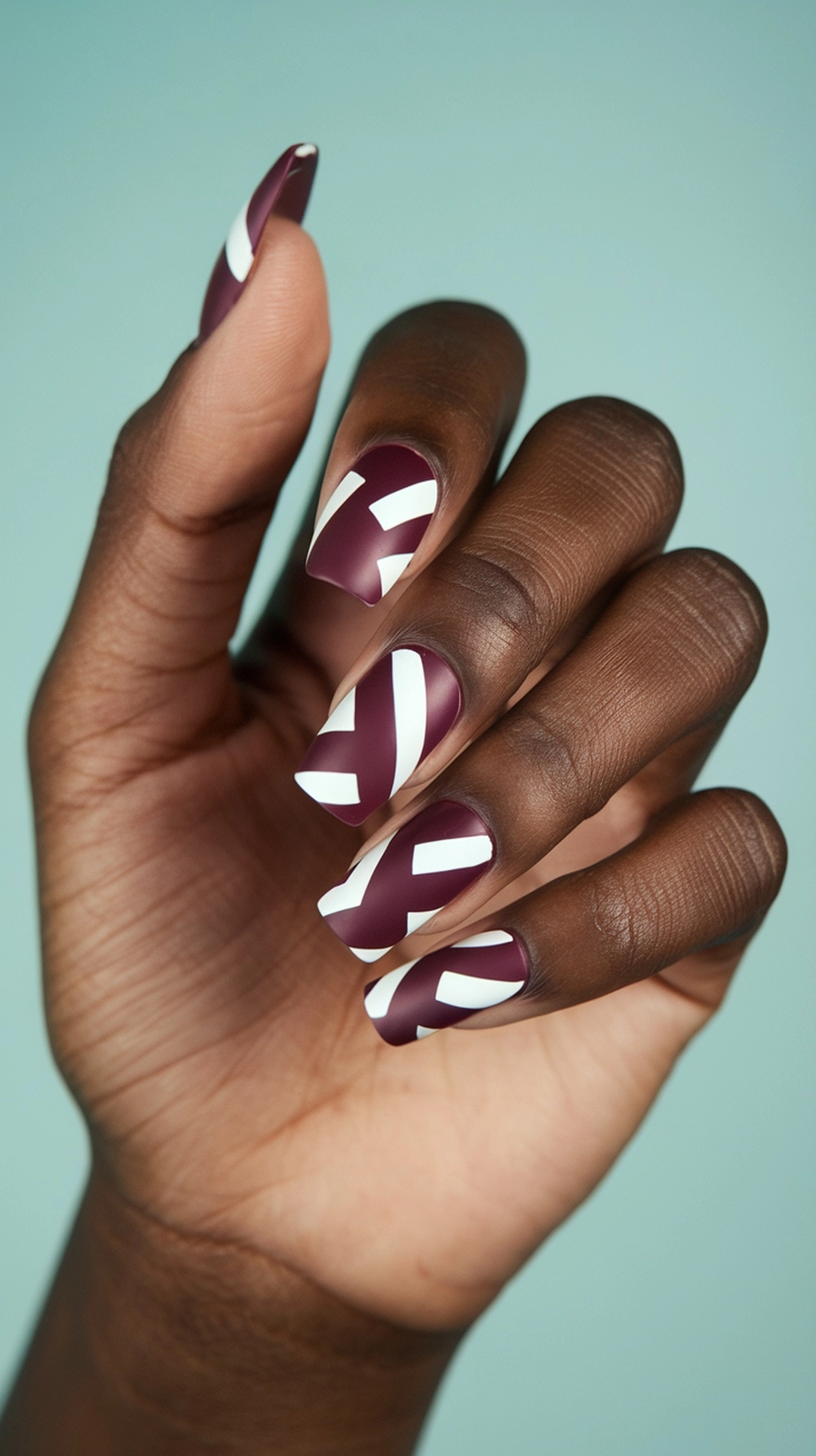 How to Style Burgundy Nail Designs for a Bold Stunning Look 7 Burgundy nails with white geometric patterns on a hand