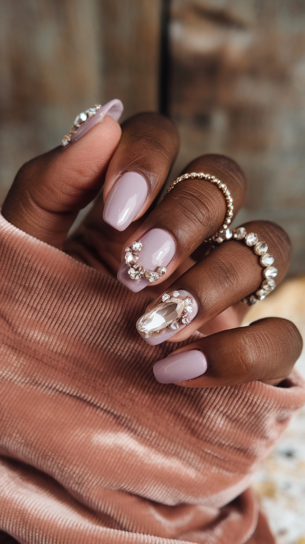 16 Cute Boho Nail Ideas You’ll Love 17 Close-up of stylish boho nails with crystal and gemstone embellishments on a hand wearing rings.