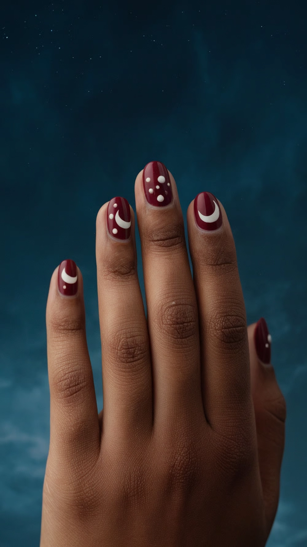 16 Cute Boho Nail Ideas You’ll Love 19 Close-up of hands with minimalist moon and star nail designs on a dark background