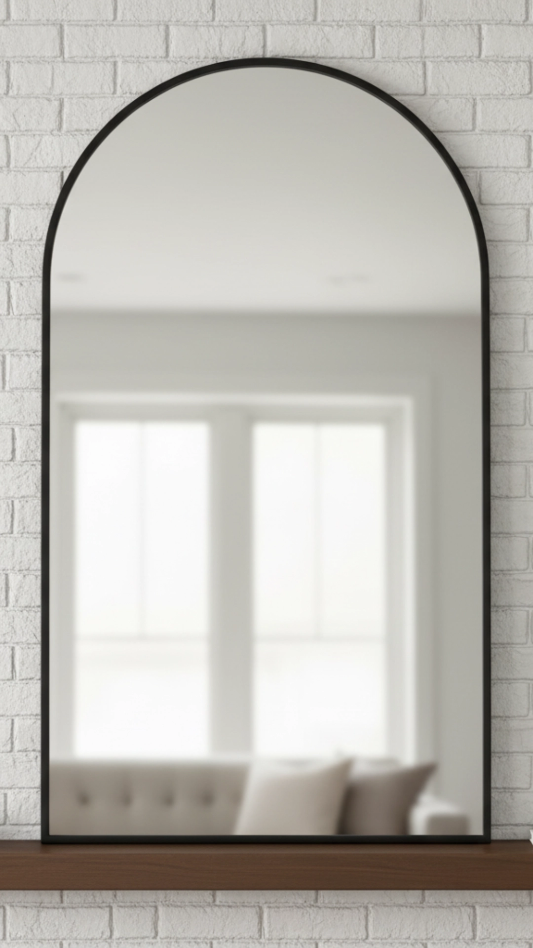 How to Layer Fall Mantle Decor (The 6-Step Guide) 4 A large, black-framed arched mirror leaning against a white brick fireplace, serving as the central anchor piece for mantle decor.