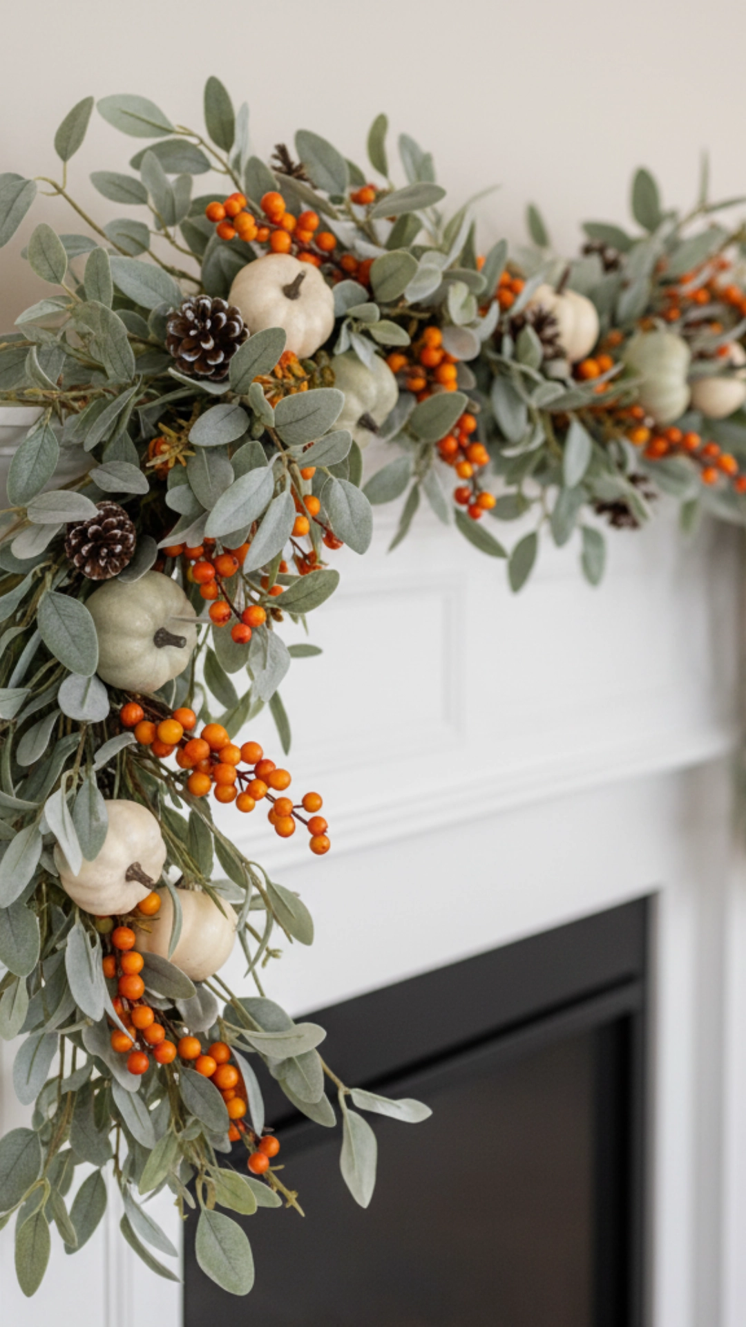How to Layer Fall Mantle Decor (The 6-Step Guide) 5 A close-up of a beautiful fall garland with orange berries drooping gracefully in an asymmetrical swoop off the side of a white mantle.