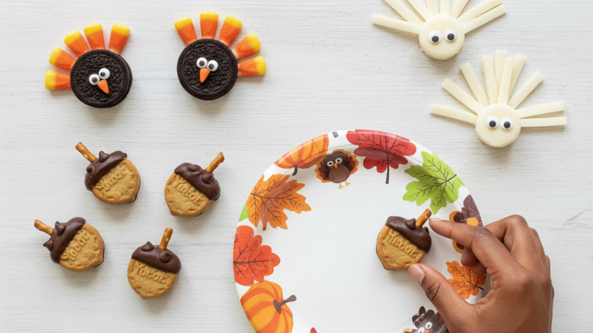 A festive flat-lay of fun Thanksgiving snacks for kids, including candy turkeys and acorns, being arranged on a platter.