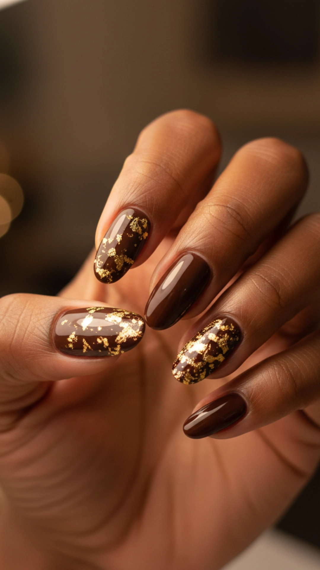 25 Jaw-Dropping Fall Nail Ideas You Must Try 4 Elegant chocolate brown nails adorned with scattered gold leaf flakes.