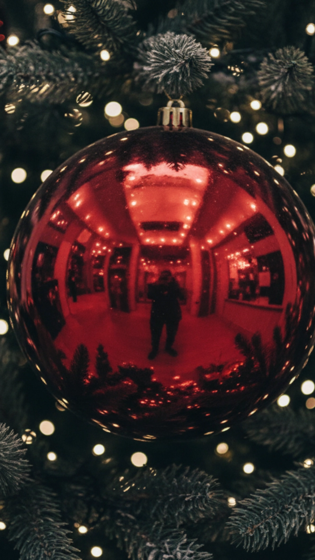 A very large, oversized red ornament making a statement on a Christmas tree.