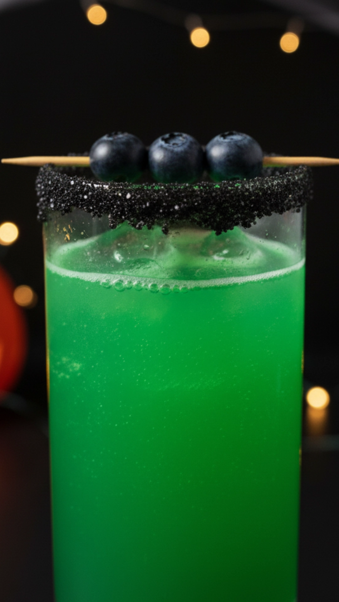 15 Fun Non Alcoholic Halloween Punch Recipes 11 A tall glass of a bright green Frankenstein-themed nonalcoholic punch with a black sugar rim and blueberry "bolts."