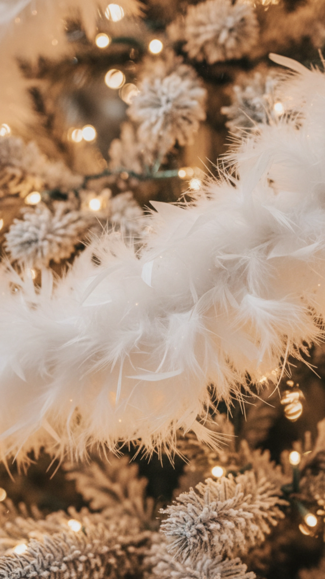 A soft white feather boa woven among the branches and lights of a Christmas tree.