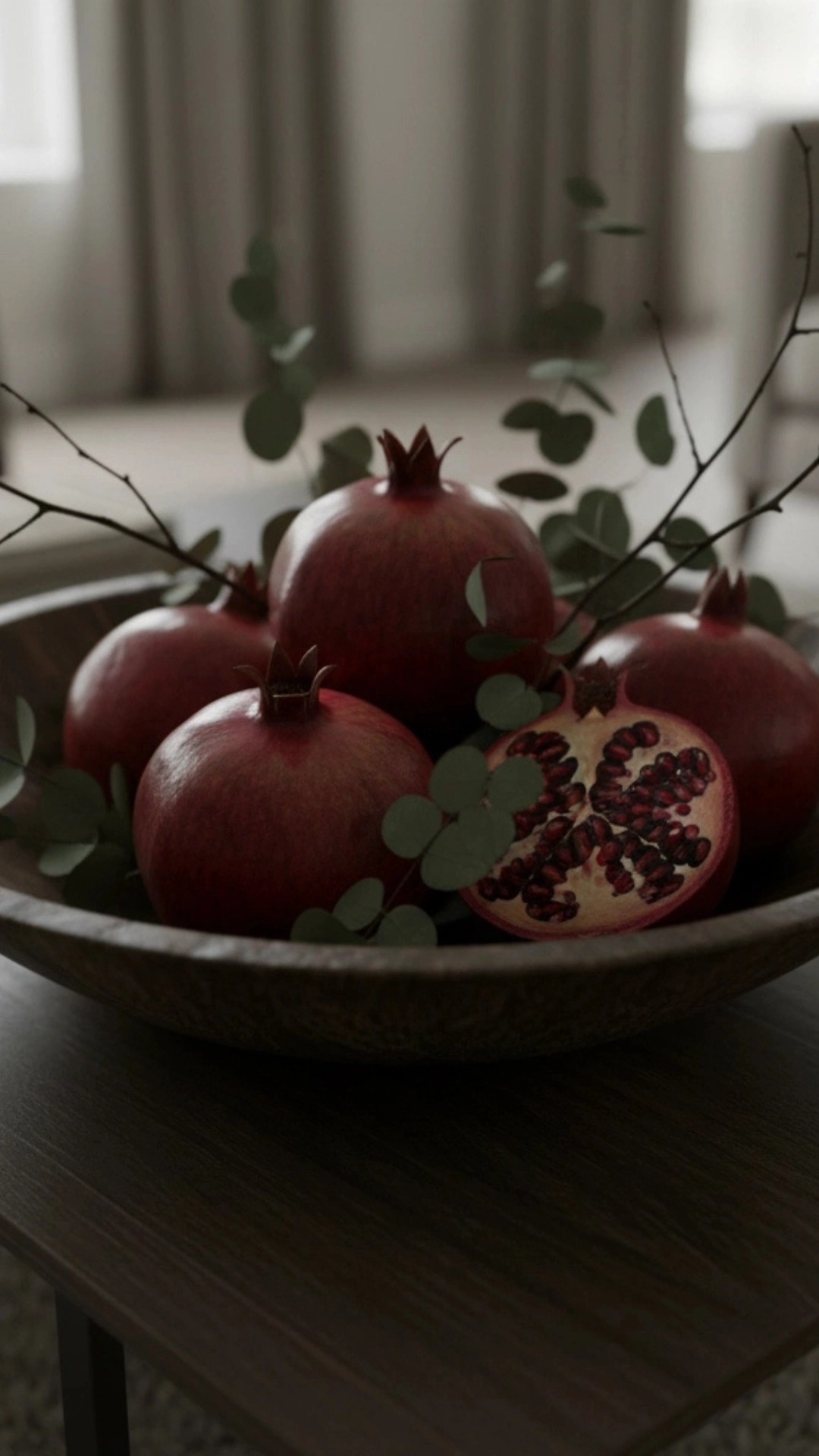 10 Insane Modern Living Room Decor Ideas for Autumn 13 A modern fall centerpiece featuring a wooden bowl filled with dark pomegranates and eucalyptus on a coffee table.