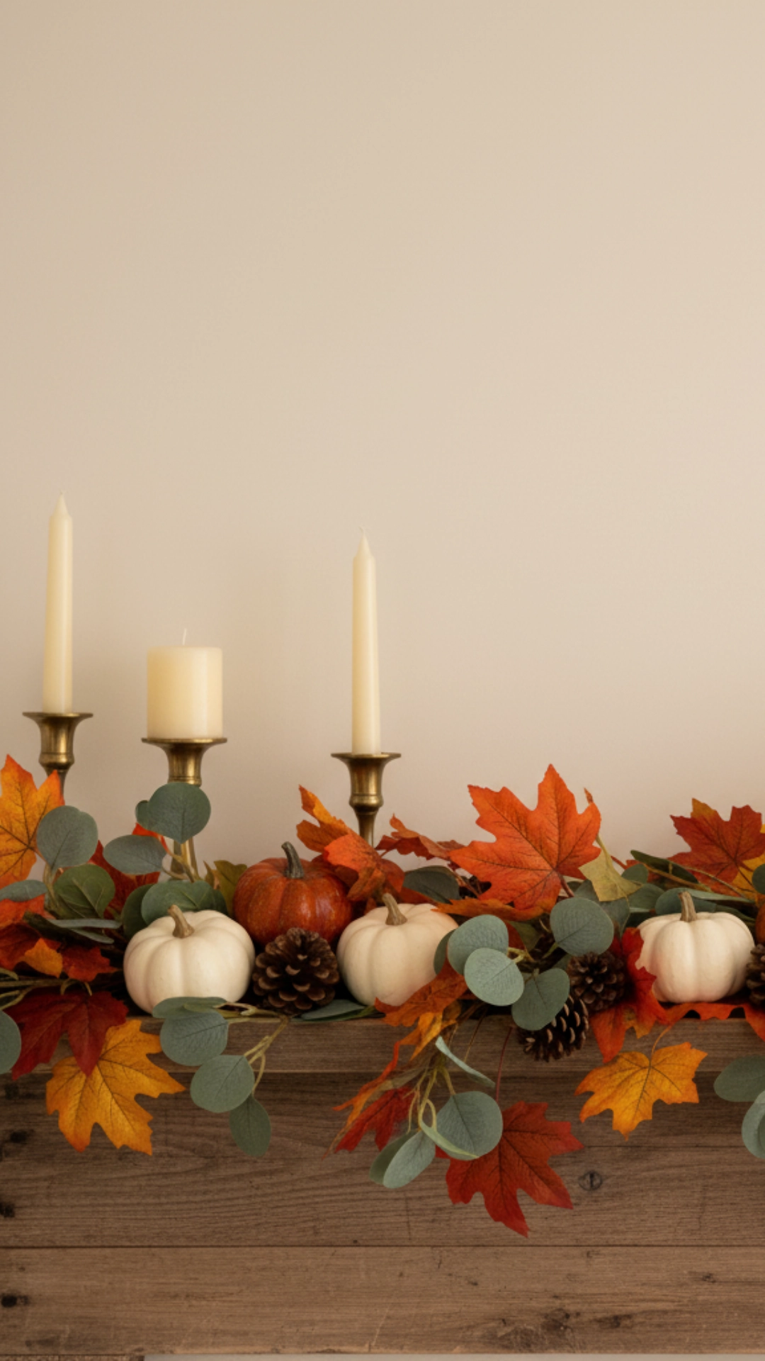 15 Unforgettable Rustic Living Room Decor Ideas 2 A close-up of a rustic wooden fireplace mantel decorated with a garland, pumpkins, pinecones, and warm flickering candles for fall.