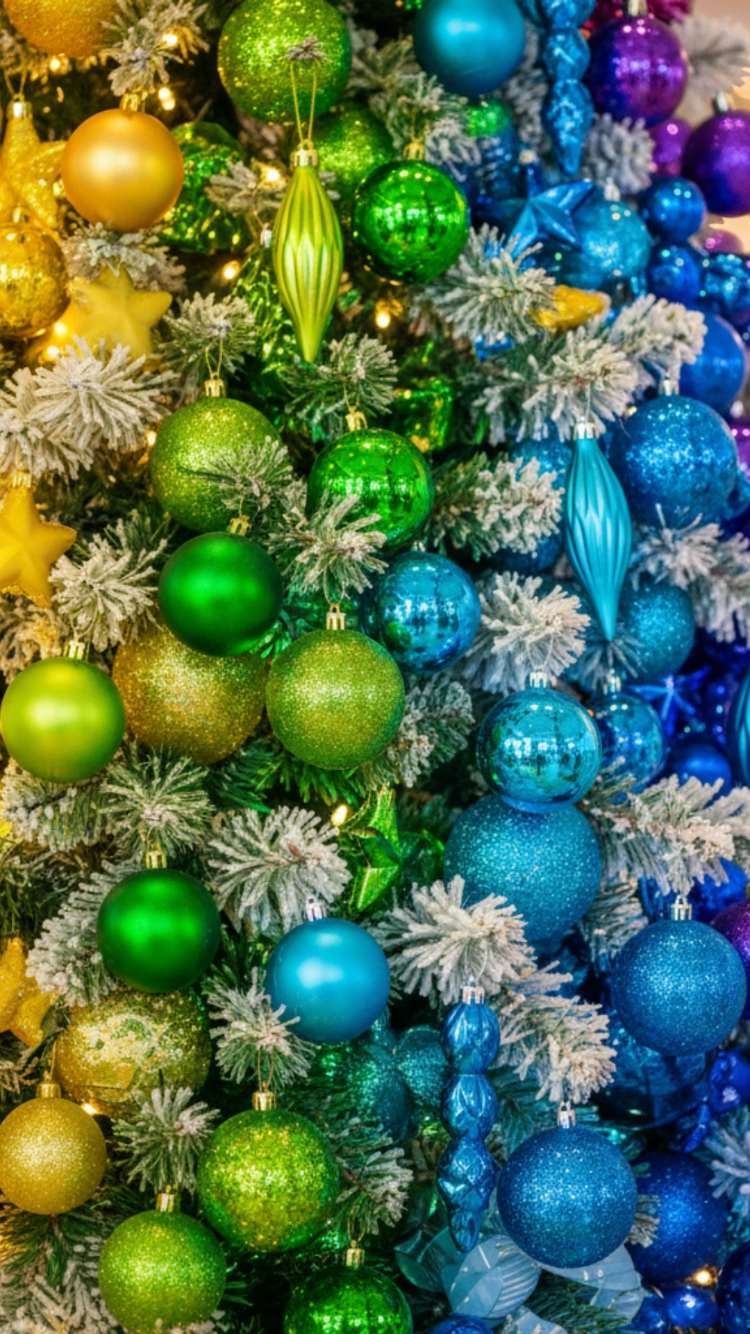 A Christmas tree with ornaments organized in a vibrant rainbow color gradient.