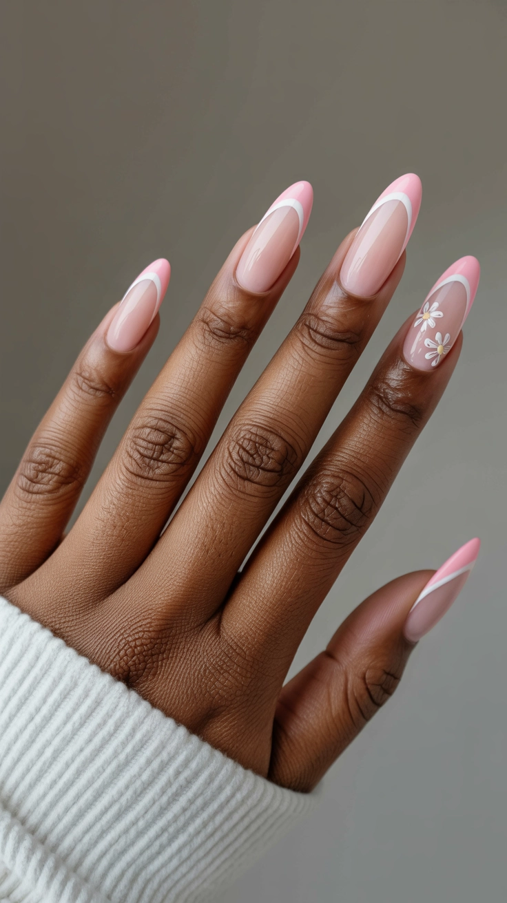 Almond-shaped nails with baby pink French tips and white floral designs.