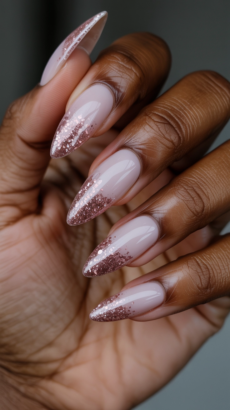Stiletto nails with a pink to rose gold glitter ombre transition.