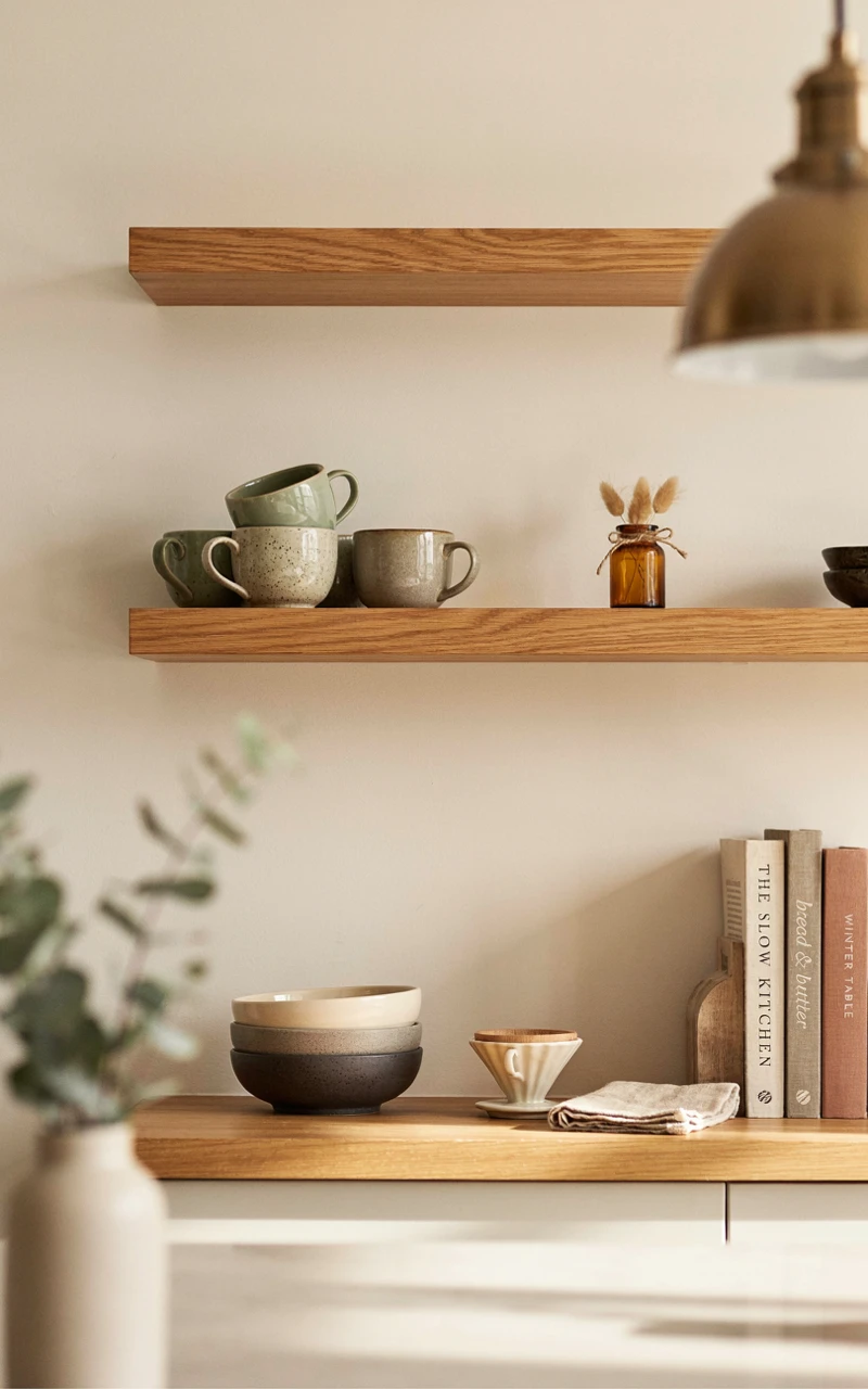 How to Style Fall Kitchen Decor for a Warm, Inviting Space 8 Open kitchen shelving styled for autumn with ceramic mugs, amber glass, and warm wood accents.