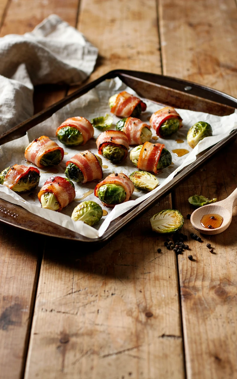 10 Thanksgiving Appetizers to Start Planning Early 5 Crispy bacon-wrapped Brussels sprouts on a parchment-lined baking sheet.