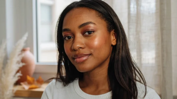 A woman wearing a white top with a soft brown fall makeup look featuring warm, natural tones.