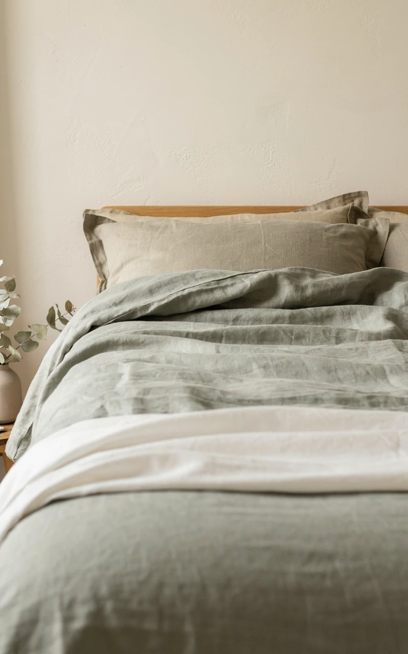 11 Greenery Bedroom Ideas for a Fresh and Cozy Space 3 A bed made with sage green linen bedding and olive pillowcases for a cozy green bedroom