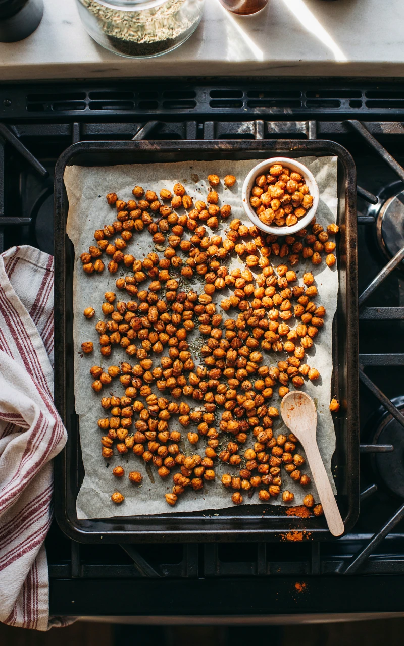 11 Healthy Snack Ideas for Any Time of Day 6 Golden roasted chickpeas with smoked paprika on a parchment-lined baking sheet, a crunchy healthy snack